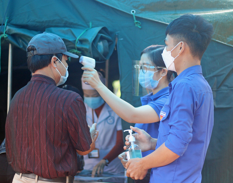 Tình nguyện viên của Thành Đoàn Pleiku hỗ trợ đo thân nhiệt người dân đến khám bệnh tại Trung tâm Y tế TP. Pleiku. Ảnh: Phan Lài