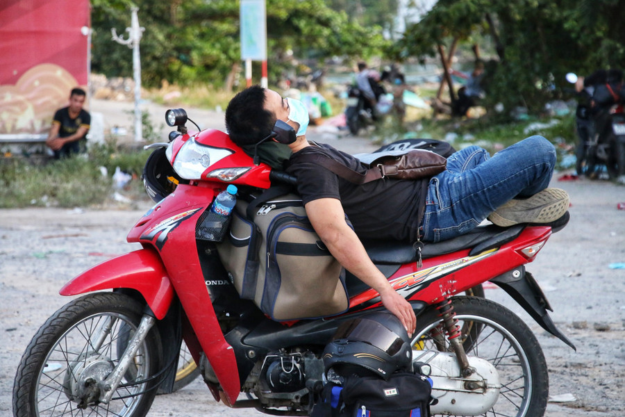 Một thanh niên nằm nghỉ ngay trên xe máy tại thị trấn Lăng Cô, sau quãng đường dài di chuyển từ miền Nam về quê ở miền Trung. Ảnh: D.B