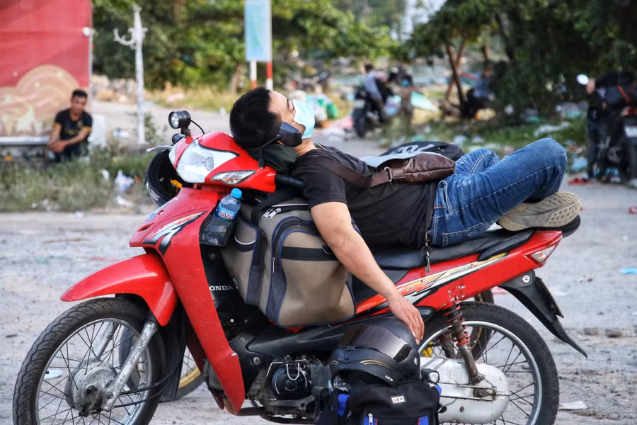 Một thanh niên nằm nghỉ ngay trên xe máy tại thị trấn Lăng Cô, sau quãng đường dài di chuyển từ miền Nam về quê ở miền Trung. Ảnh: D.B