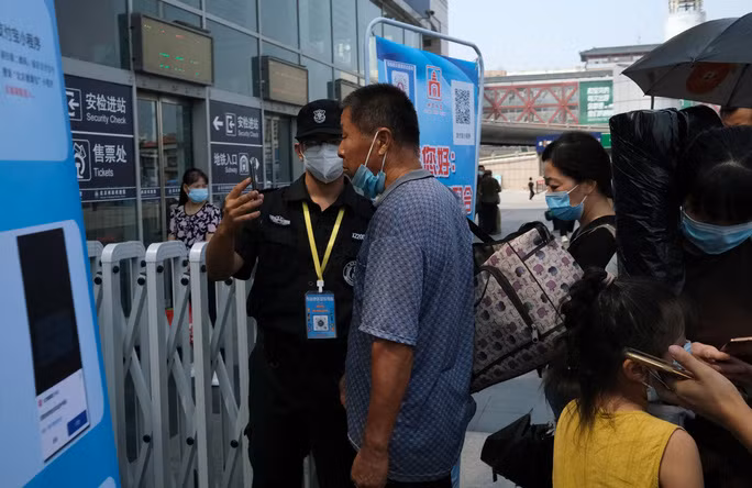 Nhân viên an ninh kiểm tra sức khỏe của một người đàn ông tại một nhà ga ở thủ đô Bắc Kinh - Trung Quốc hôm 6-8Ảnh: REUTERS