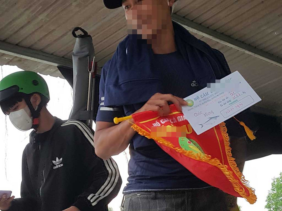 Nam thanh niên cầm cờ lưu niệm của hồ câu B.D (H.Củ Chi), giải thưởng nhất ngày là 100 triệu đồng