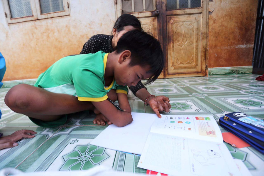 Dù bị khuyết 2 bàn tay nhưng Đức vẫn ham học và thường xuyên tập viết chữ. Ảnh: Văn Ngọc