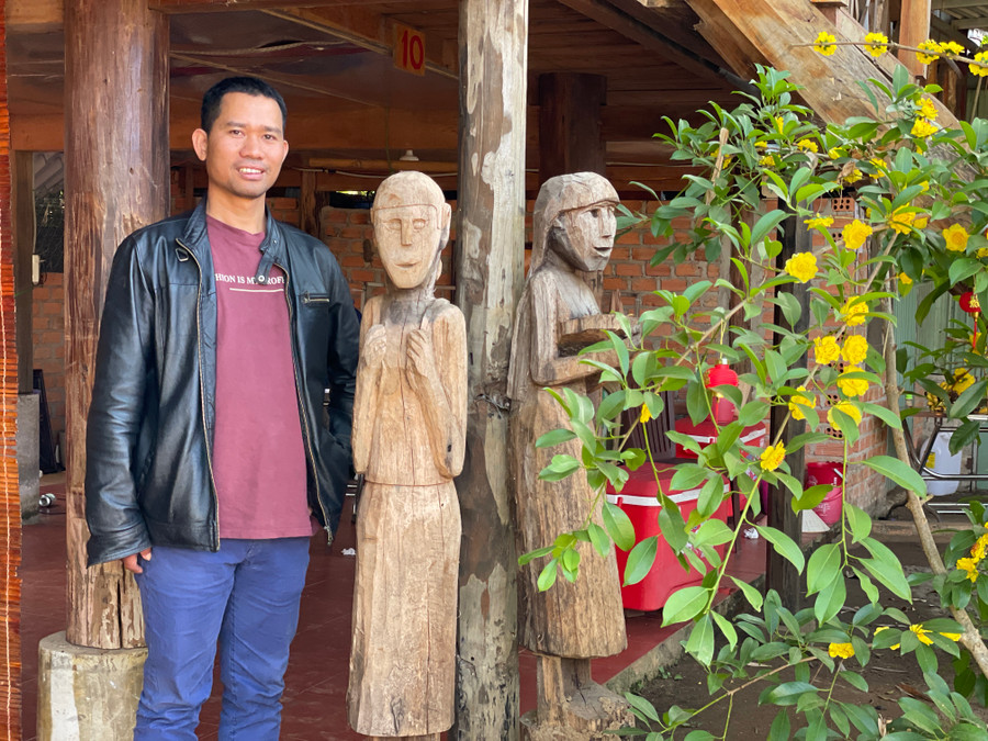 Ksor Đức bên một số tác phẩm tượng gỗ dân gian. Ảnh: Phương Duyên