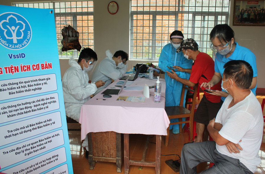 Cán bộ BHXH tỉnh Đắk Lắk thực hiện các quy định phòng chống dịch khi tiếp xúc người dân để cài đặt ứng dụng VssID. Ảnh: Trung Chuyên
