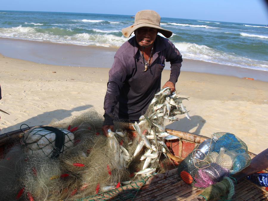 Một ngư dân khoe chiến tích sau một đêm đi biển bằng thúng tròn. Ảnh: Quang Viên