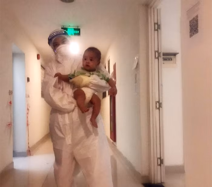 Em bé 3 tháng tuổi được điều dưỡng chăm sóc khi bà ngoại trở nặng tại bệnh viện dã chiến.