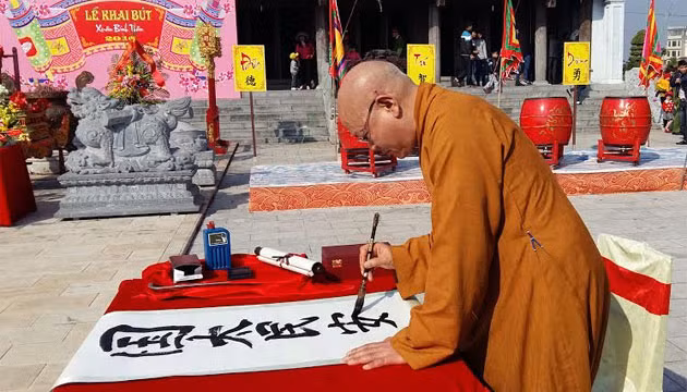 Thượng tọa Thích Quang Tùng khai bút với bức thư pháp bốn chữ “Quốc thái, dân an”. Ảnh chụp Xuân Bính Thân 2016 của NGÔ QUANG DŨNG