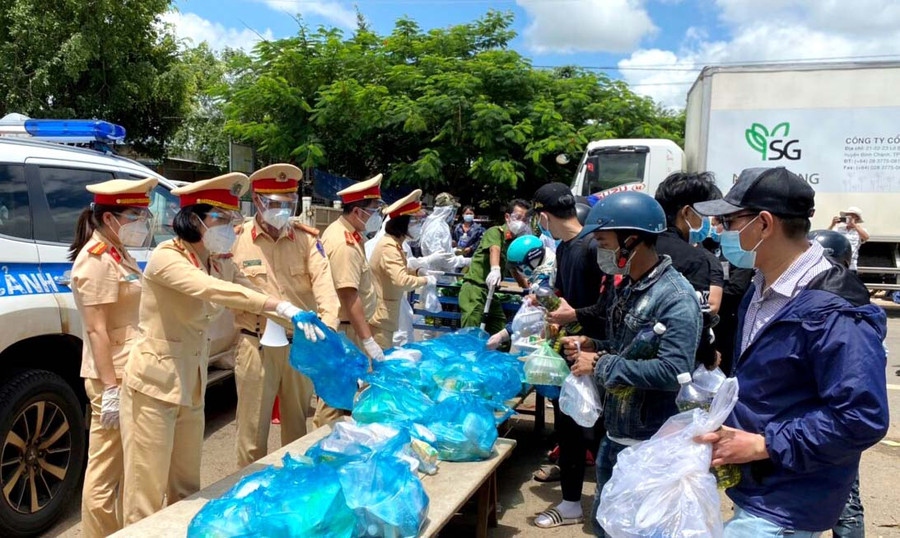 Hội viên Hội Phụ nữ Phòng Cảnh sát Giao thông phối hợp hỗ trợ người dân trở về từ các tỉnh phía Nam để phòng tránh dịch bệnh Covid-19. Ảnh: Nguyễn Hữu