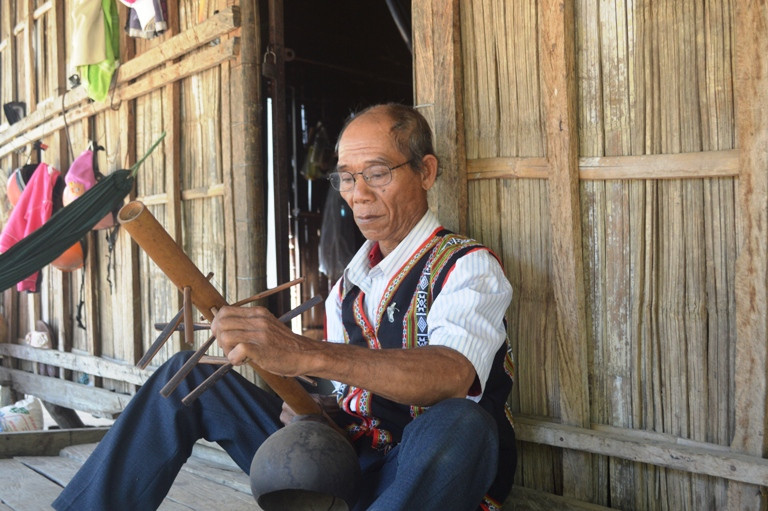 Già Đinh Du chỉnh lại cao độ cây đàn Goong của gia đình. Ảnh: Nguyễn Hiền