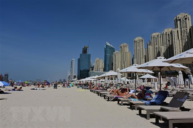 Khách du lịch tắm nắng trên bãi biển ở Dubai, UAE. Ảnh: AFP/TTXVN