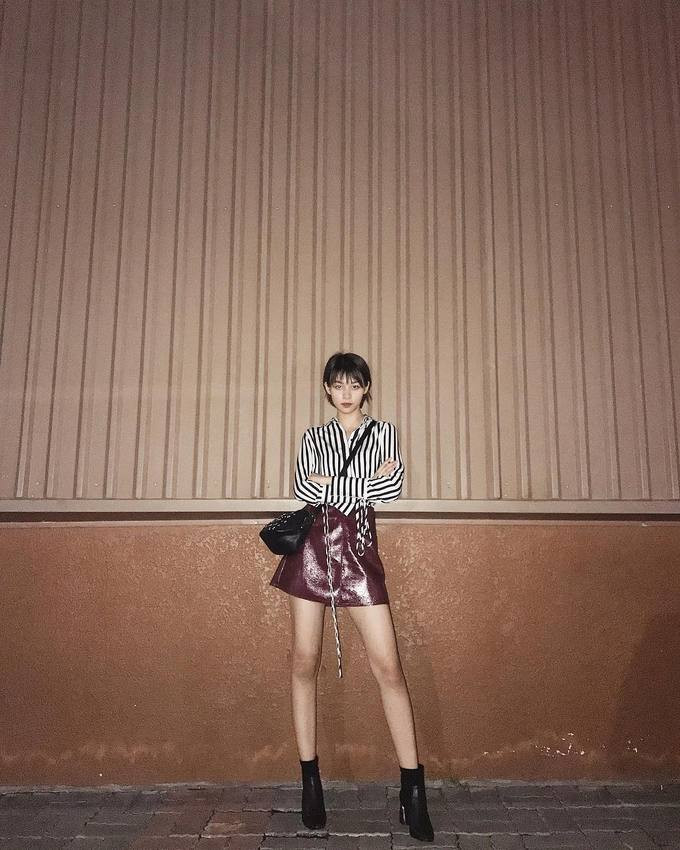 Phí Phương Anh mix áo sơ mi kẻ năng động cùng chân váy da thời thượng.