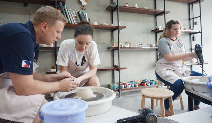 Chủ quán bar gốm, James, hướng dẫn một vị khách làm gốm. Chủ quán bar gốm, James, hướng dẫn một vị khách làm gốm.