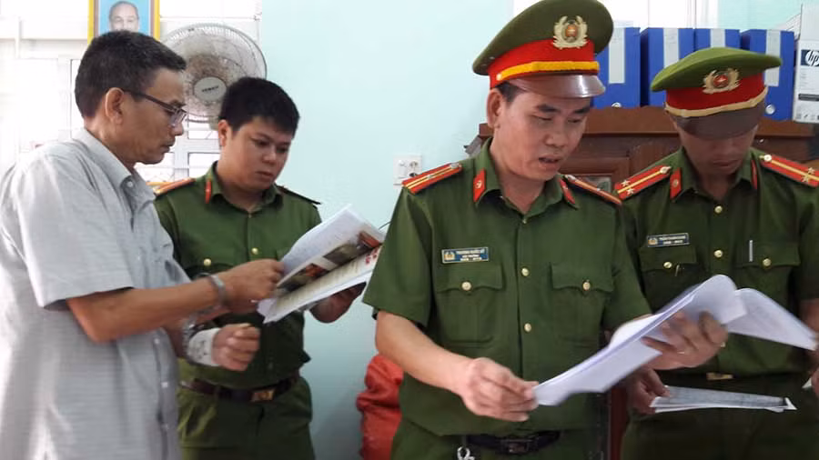  Công an huyện Vân canh thực hiện lệnh khám xét nơi làm việc của ông Hồ Văn Tèo (áo trắng bìa trái). Ảnh: Thi Phú