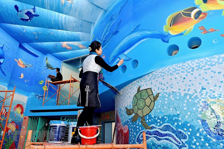 Họa sỹ Nguyễn Thu Thủy bên tác phẩm gắn gốm nghệ thuật Nhà Gương.