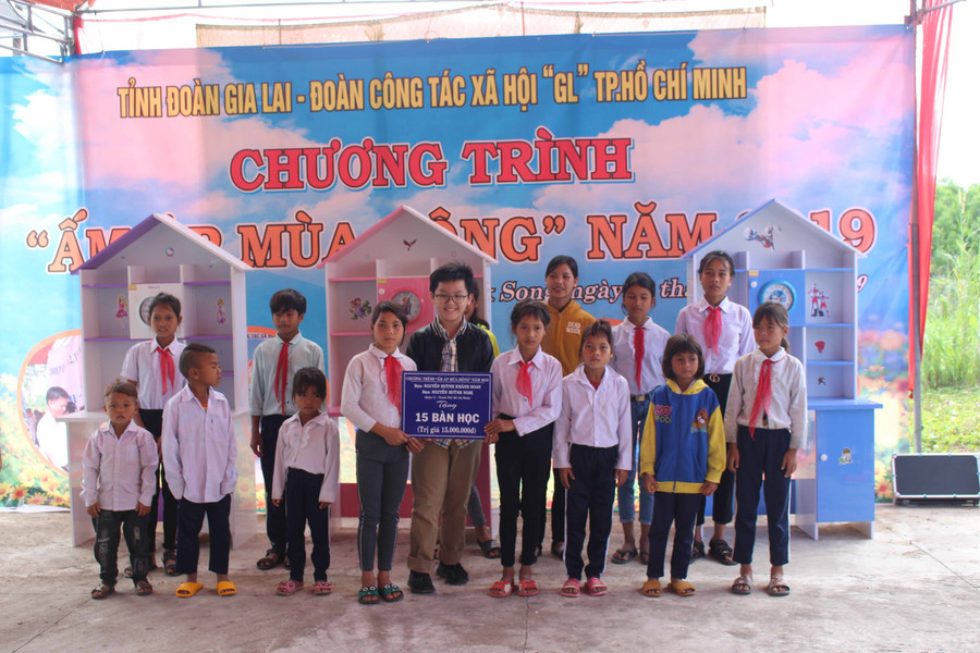Em Nguyễn Huỳnh Nghị (hàng trước, thứ 5 từ trái qua)-con trai bác sĩ Nguyễn Tri Thức tặng bàn học cho các em học sinh ở xã Đak Song. Ảnh: Phan Lài