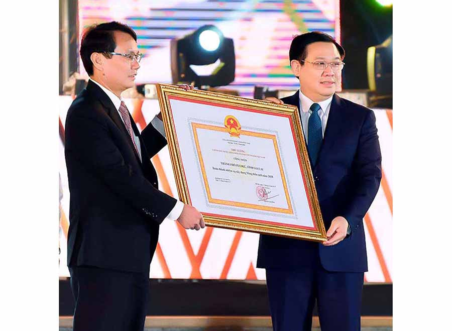 Phó Thủ tướng Chính phủ Vương Đình Huệ (bìa phải) trao quyết định công nhận TP. Pleiku hoàn thành nhiệm vụ xây dựng nông thôn mới cho Bí thư Thành ủy Pleiku Trịnh Duy Thuân.