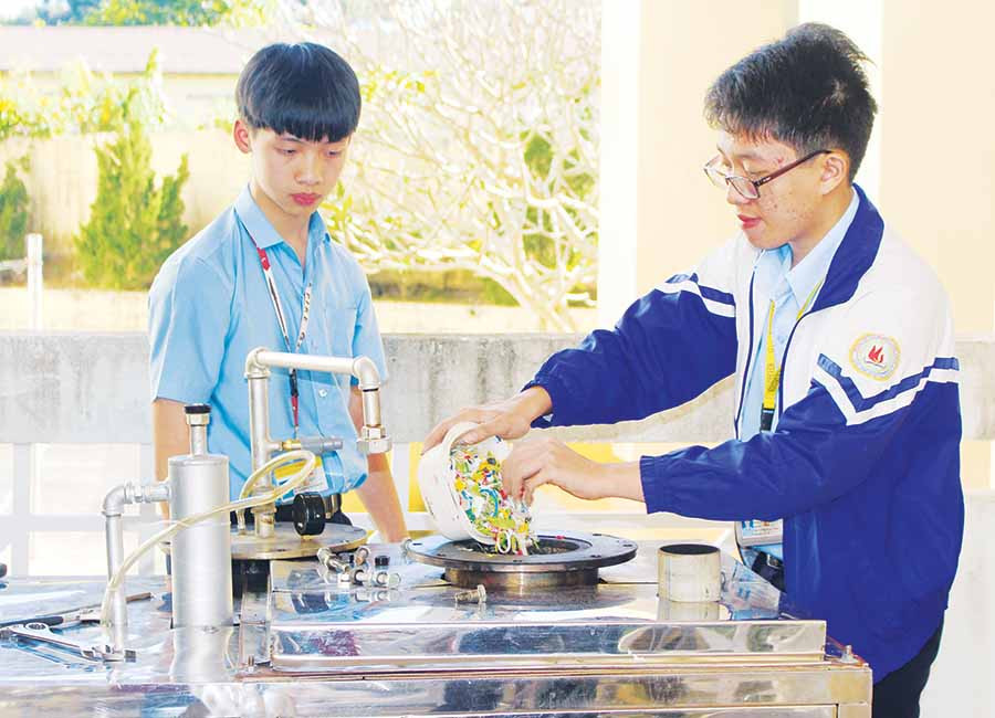 Em Bùi Mai Hoàng Nguyên (bìa trái) và em Hoàng Hưng Thịnh đang cho rác thải nhựa vào lò đốt. Ảnh: P.L  Em Bùi Mai Hoàng Nguyên (bìa trái) và em Hoàng Hưng Thịnh đang cho rác thải nhựa vào lò đốt. Ảnh: P.L