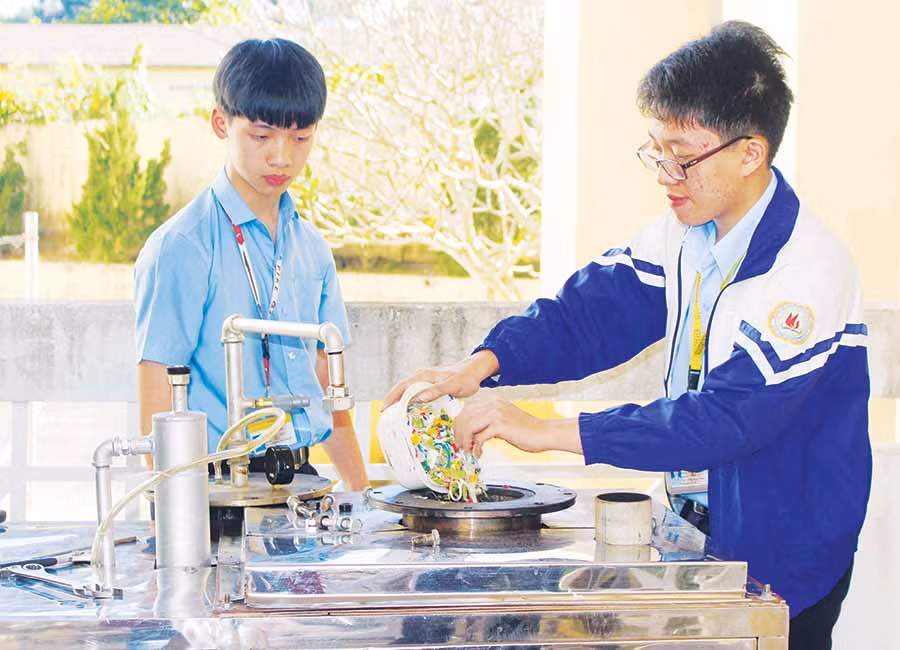  Em Bùi Mai Hoàng Nguyên (bìa trái) và em Hoàng Hưng Thịnh đang cho rác thải nhựa vào lò đốt. Ảnh: P.L