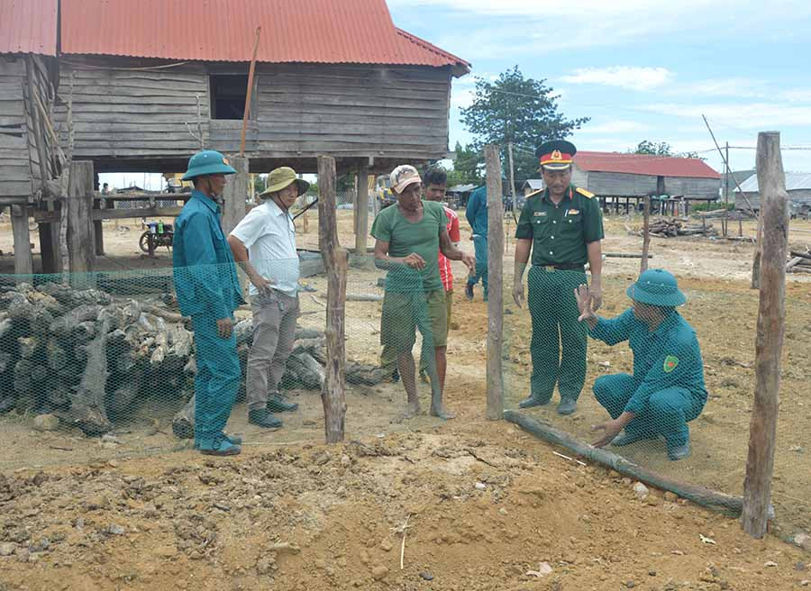 Lực lượng vũ trang huyện Phú Thiện hướng dẫn người dân làm hàng rào, vườn rau. Ảnh: Anh Huy