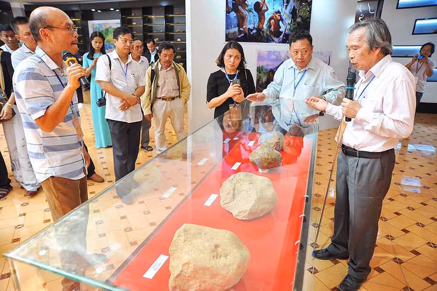  Phó Giáo sư-Tiến sĩ Nguyễn Khắc Sử (bìa phải) giới thiệu một số hiện vật khảo cổ học khai quật tại Di tích sơ kỳ Đá cũ An Khê. Ảnh: H.N