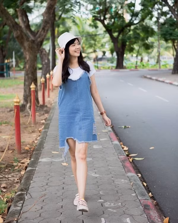 Người đẹp Thái Lan chọn trang phục “Sương sương” với đầm hai dây jeans mix cùng áo thun cùng mũ xô khi ra phố