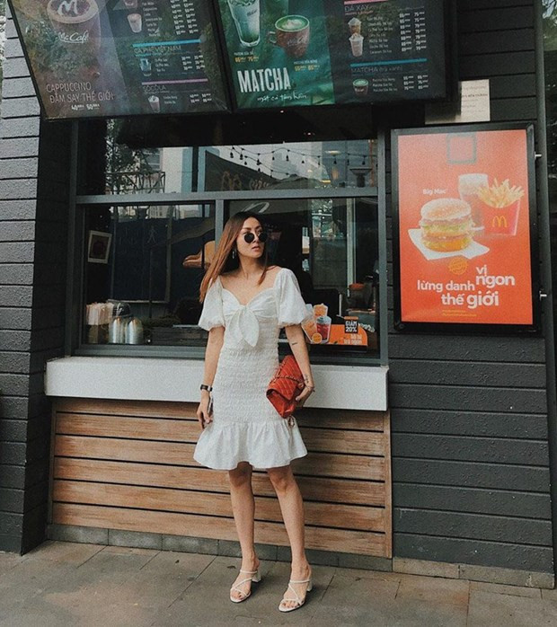  Yến Nhi hóa tiểu thư ''bánh bèo'' trong chiếc đầm trắng tay phồng, xếp nếp yểu điệu. Nữ ca sỹ kết hợp sandals tiệp màu, ''thổi bừng'' sức sống cho bộ cánh bằng túi đỏ của Chanel.