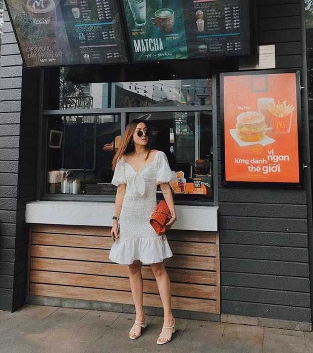  Yến Nhi hóa tiểu thư ''bánh bèo'' trong chiếc đầm trắng tay phồng, xếp nếp yểu điệu. Nữ ca sỹ kết hợp sandals tiệp màu, ''thổi bừng'' sức sống cho bộ cánh bằng túi đỏ của Chanel.