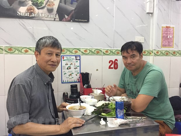 Anh Zhenya (bên phải) và người bạn Trần Vi Lăng thưởng thức bún chả ở Hà Nội. (Ảnh do nhân vật cung cấp/Vietnam+)