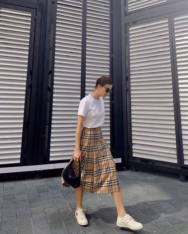  Salim pha trộn cảm hứng cổ điển và hiện đại với áo phông trắng cùng chân váy kẻ nove của Burberry. Phụ kiện túi xách quai ngắn của Prada và giày thể thao Converse x Comme des Garçons mang tới hai sắc thái đối lập song lại hòa hợp trong tổng thể trang phục.