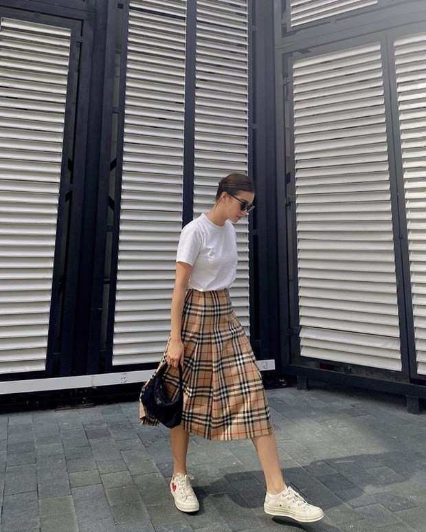  Salim pha trộn cảm hứng cổ điển và hiện đại với áo phông trắng cùng chân váy kẻ nove của Burberry. Phụ kiện túi xách quai ngắn của Prada và giày thể thao Converse x Comme des Garçons mang tới hai sắc thái đối lập song lại hòa hợp trong tổng thể trang phục.