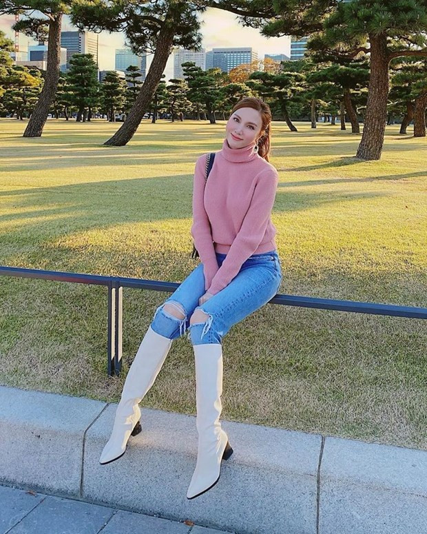 Hạnh Sino duyên dáng trong chiếc áo len cổ lọ màu hồng phấn, kết hợp cùng quần jeans rách gối và boots cao cổ tươi sáng.