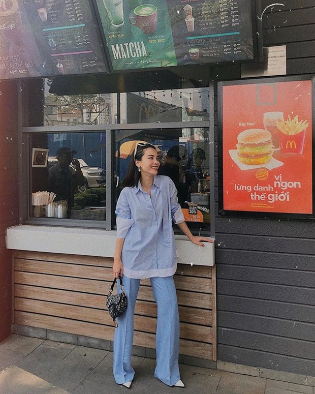 Chọn tông màu xanh pastel làm chủ đạo, Yến Trang ghép cặp sơmi dáng rộng phom dài với quần ống loe, điểm trang túi Dior họa tiết oblique.