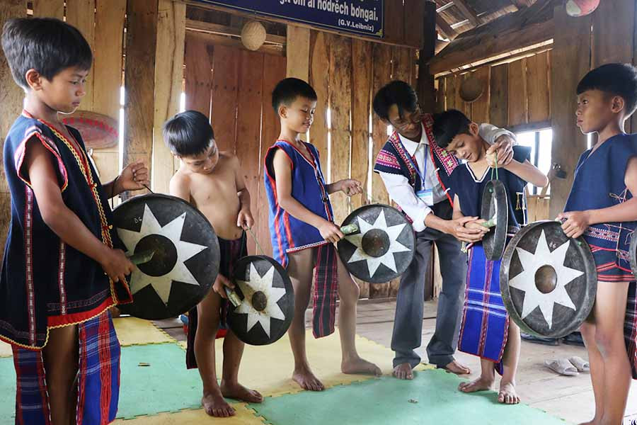  Thầy Đinh Văn Khoa (thứ 3 bên phải) hướng dẫn cách đánh cồng chiêng cho các em học sinh điểm trường 3 làng xã Tú An. Ảnh: N.M