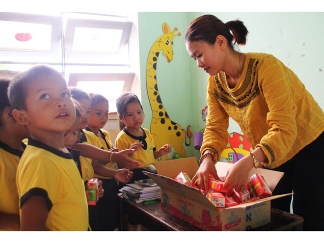 Cô Trần Thị Cư đang phát sữa cho học sinh- Ảnh: MẠNH CƯỜNG