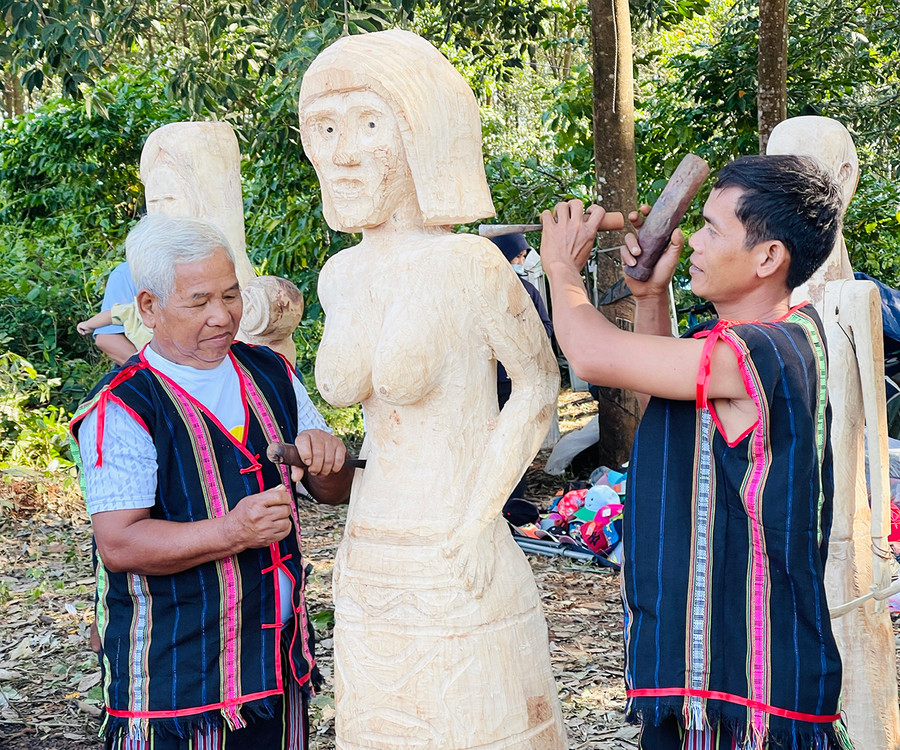  Ông Ksor Cân (bìa trái) hướng dẫn người dân trong làng tạc tượng. Ảnh: Mai Ka