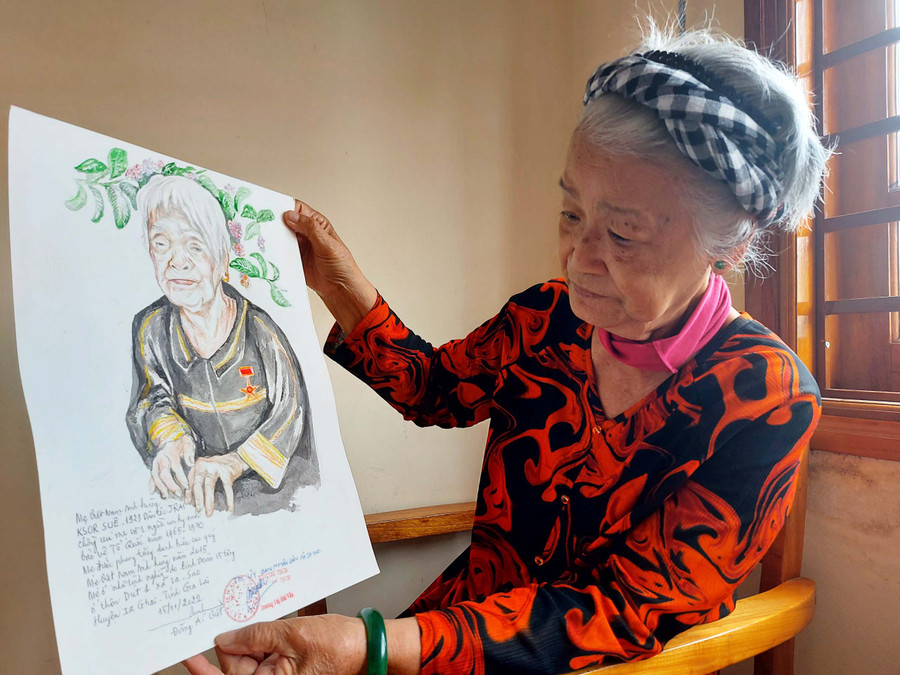 Họa sĩ Đặng Ái Việt và bức chân dung vẽ Mẹ Việt Nam Anh hùng Ksor Suê ở xã Ia Sao, huyện Ia Grai. Ảnh: Hoành Sơn