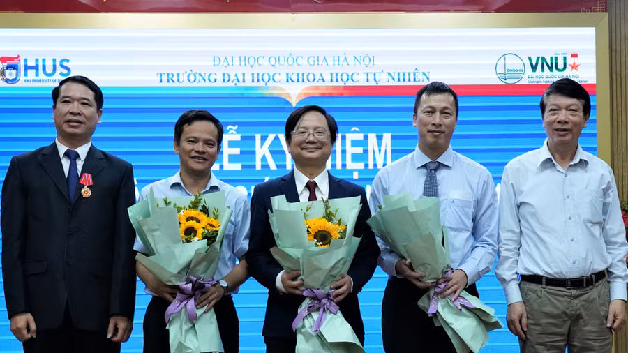 Các nhà giáo của Trường ĐH Khoa học tự nhiên, ĐH Quốc gia Hà Nội (3 người ở giữa) nhận hoa chúc mừng vì mới được công nhận đạt tiêu chuẩn giáo sư. Ảnh: HUS