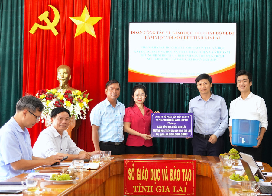 Đại diện Công ty cổ phần Xúc tiến Đầu tư và Phát triển bền vững (thứ 2 từ phải sang) trao bảng tượng trưng 6.000 bình lọc nước trị giá 6,6 tỷ đồng cho Sở GD-ĐT Gia Lai. Ảnh: Mộc Trà