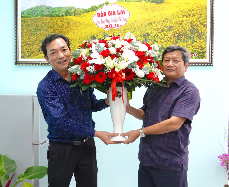 Ông Ngô Khắc Ngọc (bìa phải)-Hiệu trưởng Trường Chính trị tỉnh nhận lẵng hoa chúc mừng từ Phó Tổng Biên tập Báo Gia Lai Lương Văn Danh.