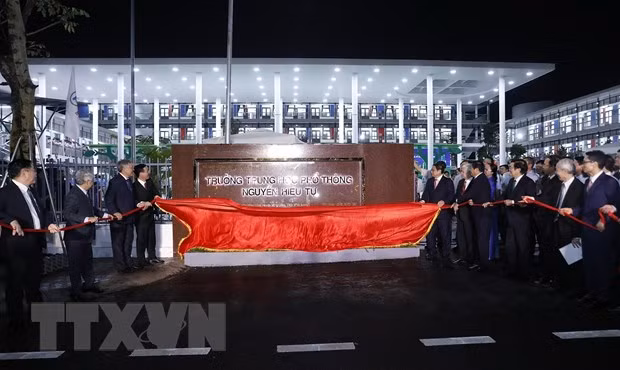 Thủ tướng Phạm Minh Chính và các đại biểu thực hiện nghi thức kéo băng khánh thành Trường Trung học phổ thông Nguyễn Hiếu Tự. (Ảnh: Dương Giang/TTXVN)