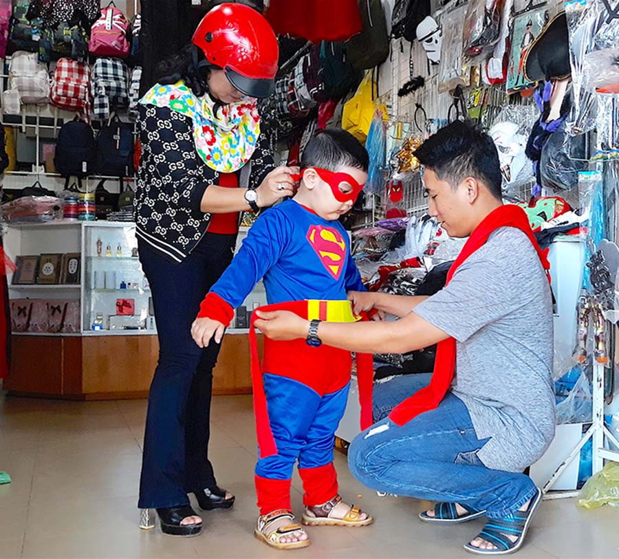 Chị Trần Thị Huệ (phường Hoa Lư, TP. Pleiku) giúp con trai thử bộ trang phục siêu nhân vừa chọn mua. Ảnh: H.T  Chị Trần Thị Huệ (phường Hoa Lư, TP. Pleiku) giúp con trai thử bộ trang phục siêu nhân vừa chọn mua. Ảnh: H.T