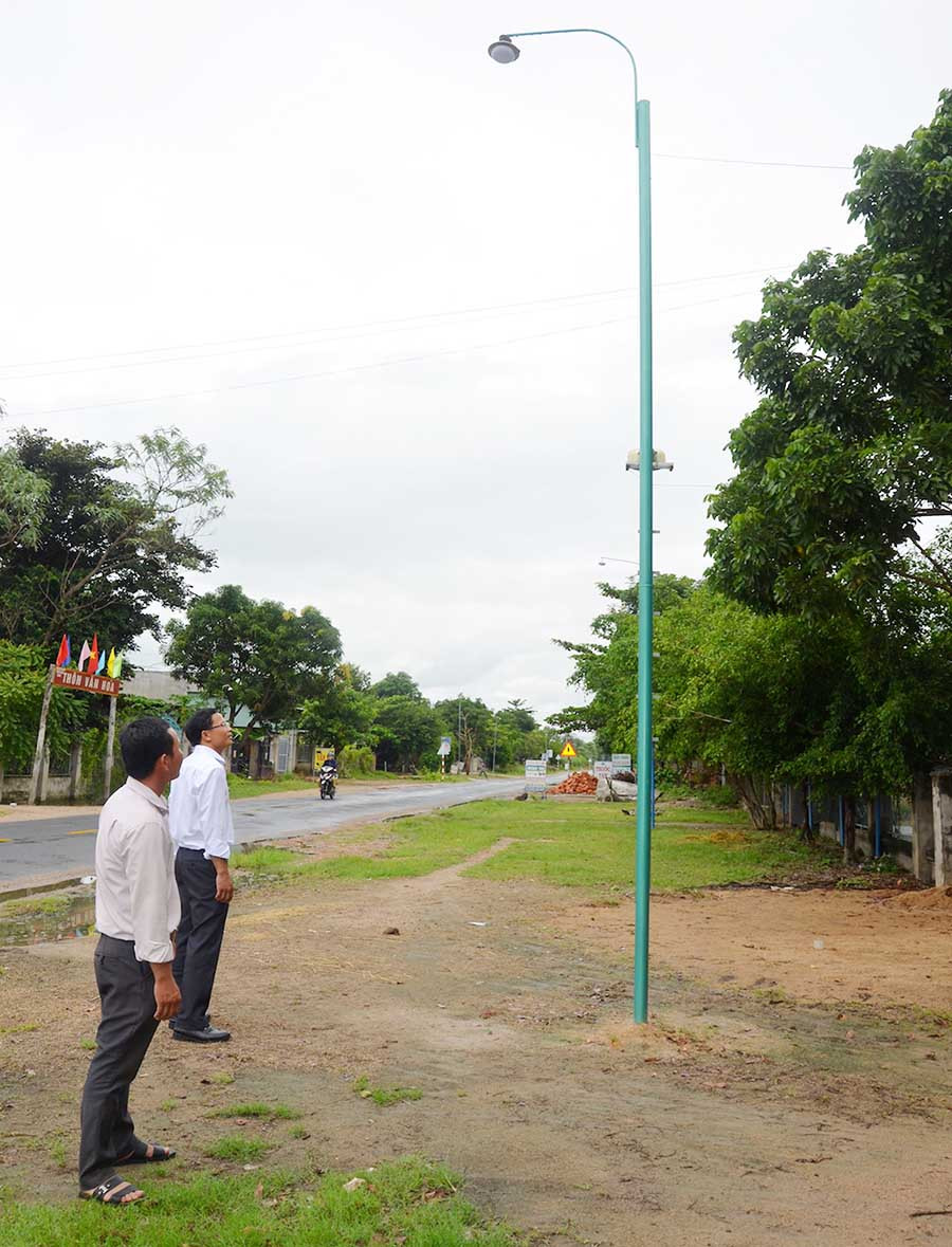 Ông Phạm Văn Phương (bên phải) kiểm tra việc kéo điện thắp sáng đường quê. Ảnh: Trần Đức