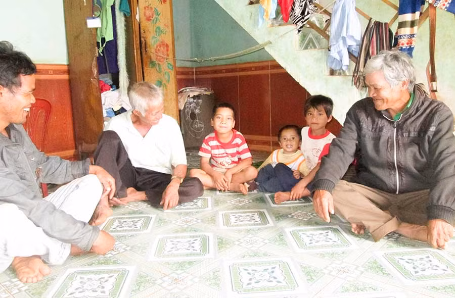 Già làng Rơ Châm Ly (áo đen bên phải) thường xuyên tới từng nhà động viên các cháu tới trường. Ảnh: Trần Dung