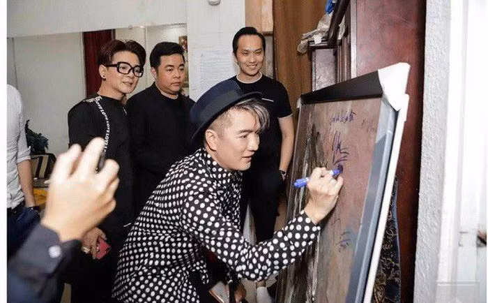 Đàm Vĩnh Hưng ký tên vào bức tranh đấu giá.