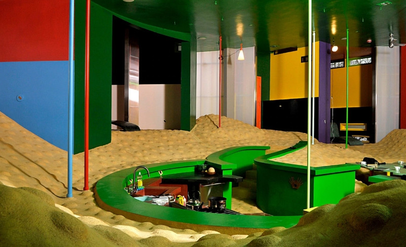  Bếp nằm chính giữa nhà. Sàn nhà không bằng phẳng mà uốn lượn nhẹ nhàng và có những chi tiết lồi lõm như bề mặt mặt trăng, để khi di chuyển, người ở có thể vận động nhẹ nhàng, tiêu hao năng lượng một cách tích cực và gia tăng cảm giác nơi bàn chân, giúp tăng cường sức mạnh đôi chân.