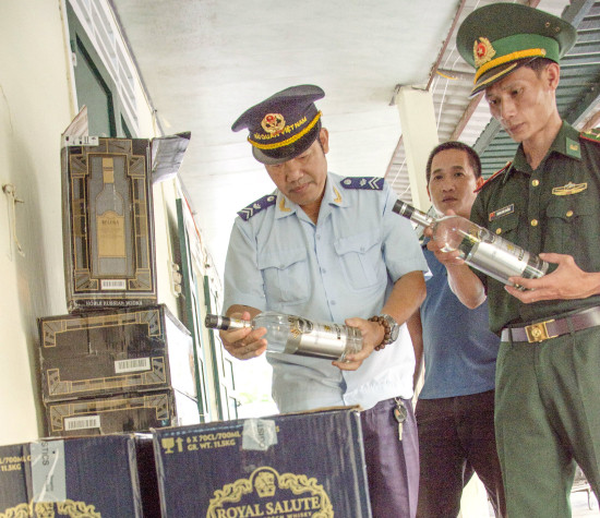 Cán bộ Biên phòng và Hải quan kiểm tra tang vật rượu ngoại lậu bị giữ. Ảnh: Văn Chương