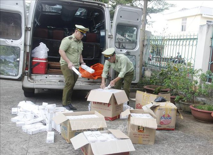 Lực lượng chức năng kiểm tra các thùng carton chứa thuốc lá điếu ngoại nhập. Ảnh: TTXVN phát Lực lượng chức năng kiểm tra các thùng carton chứa thuốc lá điếu ngoại nhập. Ảnh: TTXVN phát
