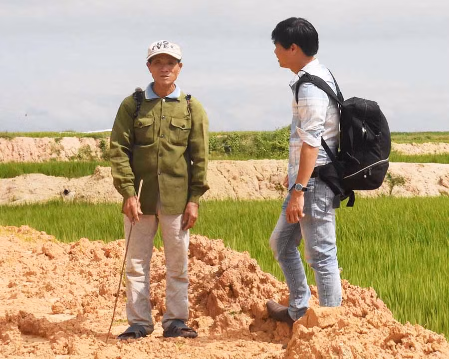 Tác giả (bìa phải) trò chuyện với một người dân ở xã Ia Yeng đã phá bỏ diện tích mía để trồng lúa. Ảnh: N.S