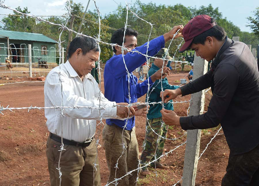 Già làng Siu Bình (áo trắng) giúp người dân chỉnh lại hàng rào. Ảnh: A.H Già làng Siu Bình (áo trắng) giúp người dân chỉnh lại hàng rào. Ảnh: A.H