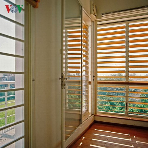 Hệ chớp lật được thiết kế và thi công… thủ công với khung thép và cấu kiện của hệ chớp lật nhôm – kính, nhưng lá chớp được thay bằng gỗ. Hệ chớp cho phép điều chỉnh độ nghiêng để “lọc sáng”. Bên trong là cửa kính để có thể đóng lại khi cần thiết.